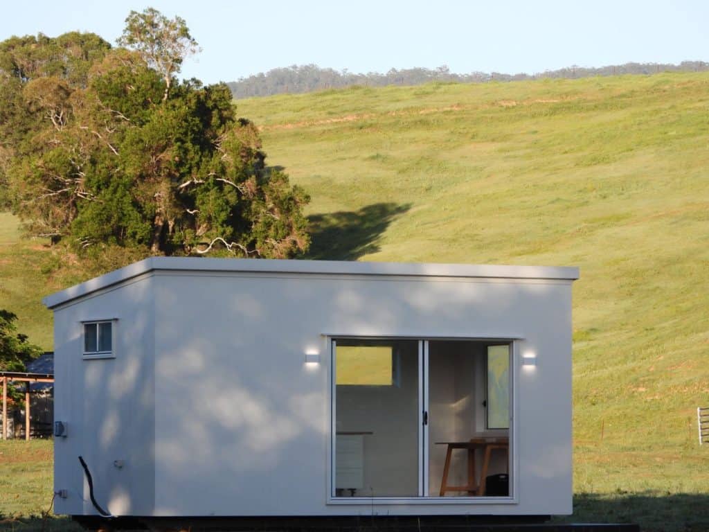 Outhaus module on a grassed slope with open paddock behind