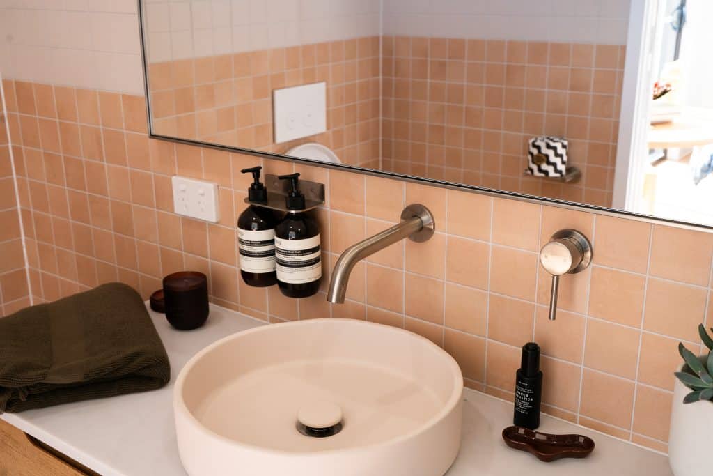 Bathroom vanity with terracotta tiles, round basin and brass tapware in an Outhaus module