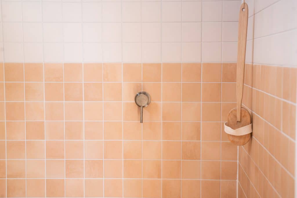 Terracotta tiled shower with brass rail in an Outhaus module bathroom