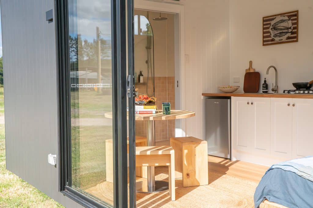 View through open sliding doors into the kitchen and bedroom of an Outhaus module
