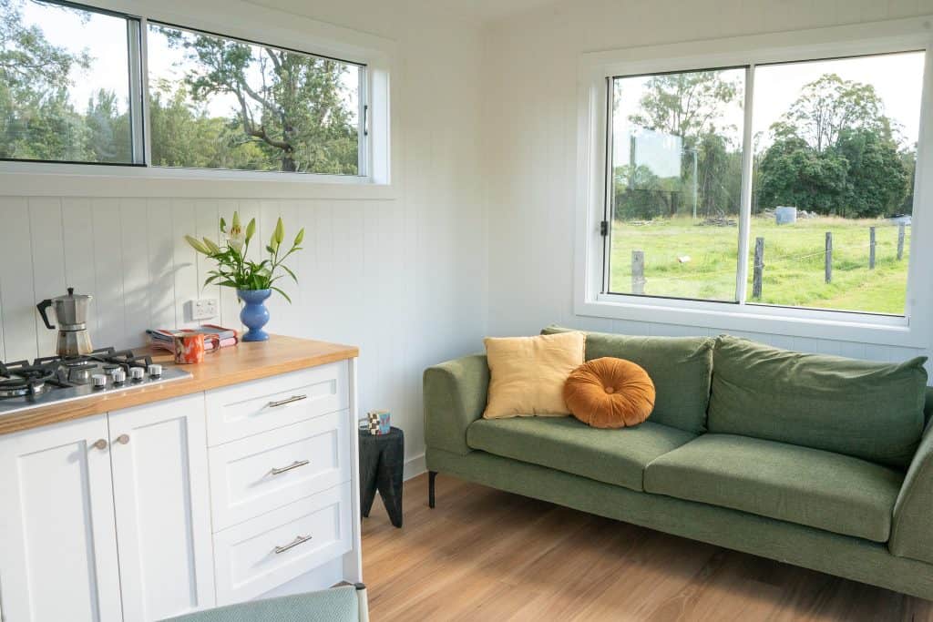 Kitchen and green sofa with a garden outlook inside an Outhaus module