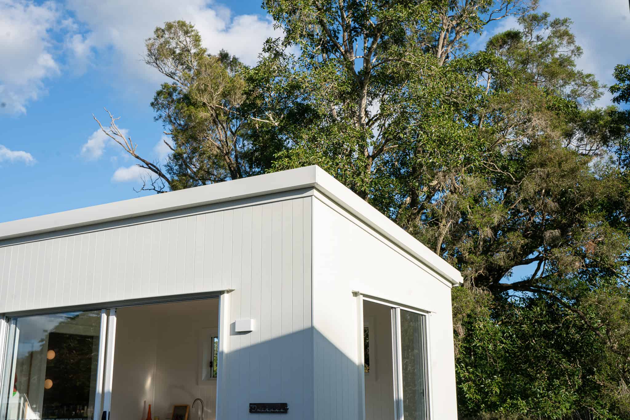 White Outhaus module with skillion roof against trees and sky