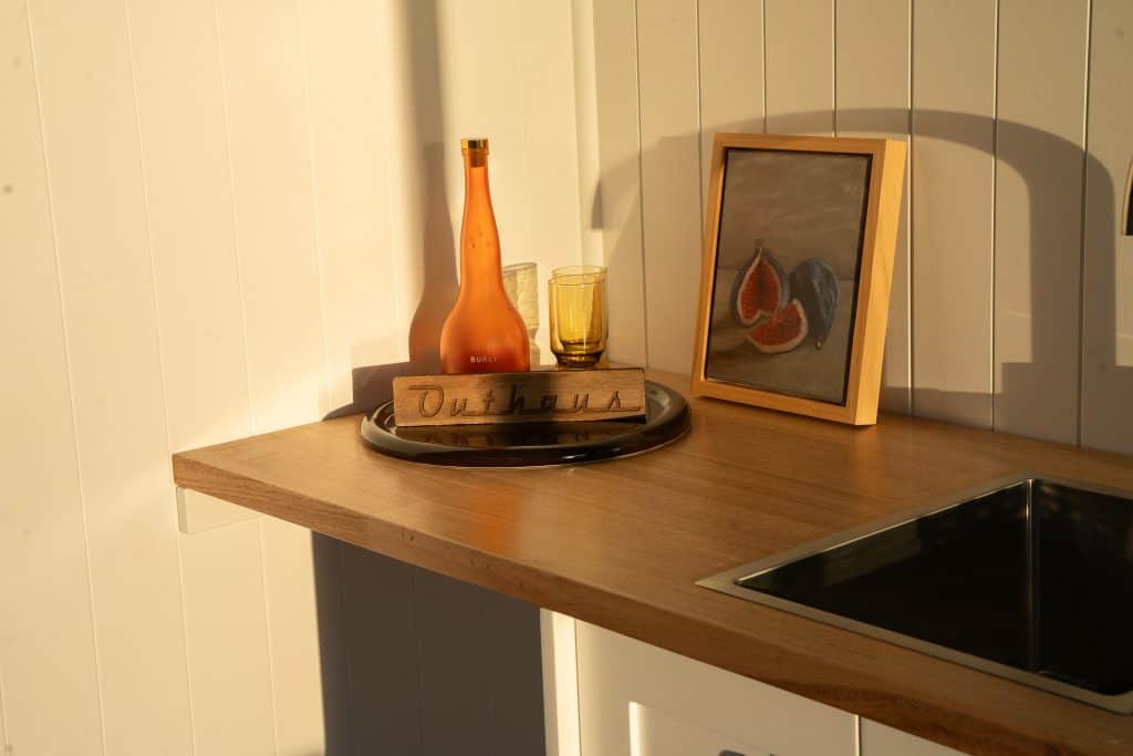 Timber benchtop with sink and styling details inside an Outhaus module