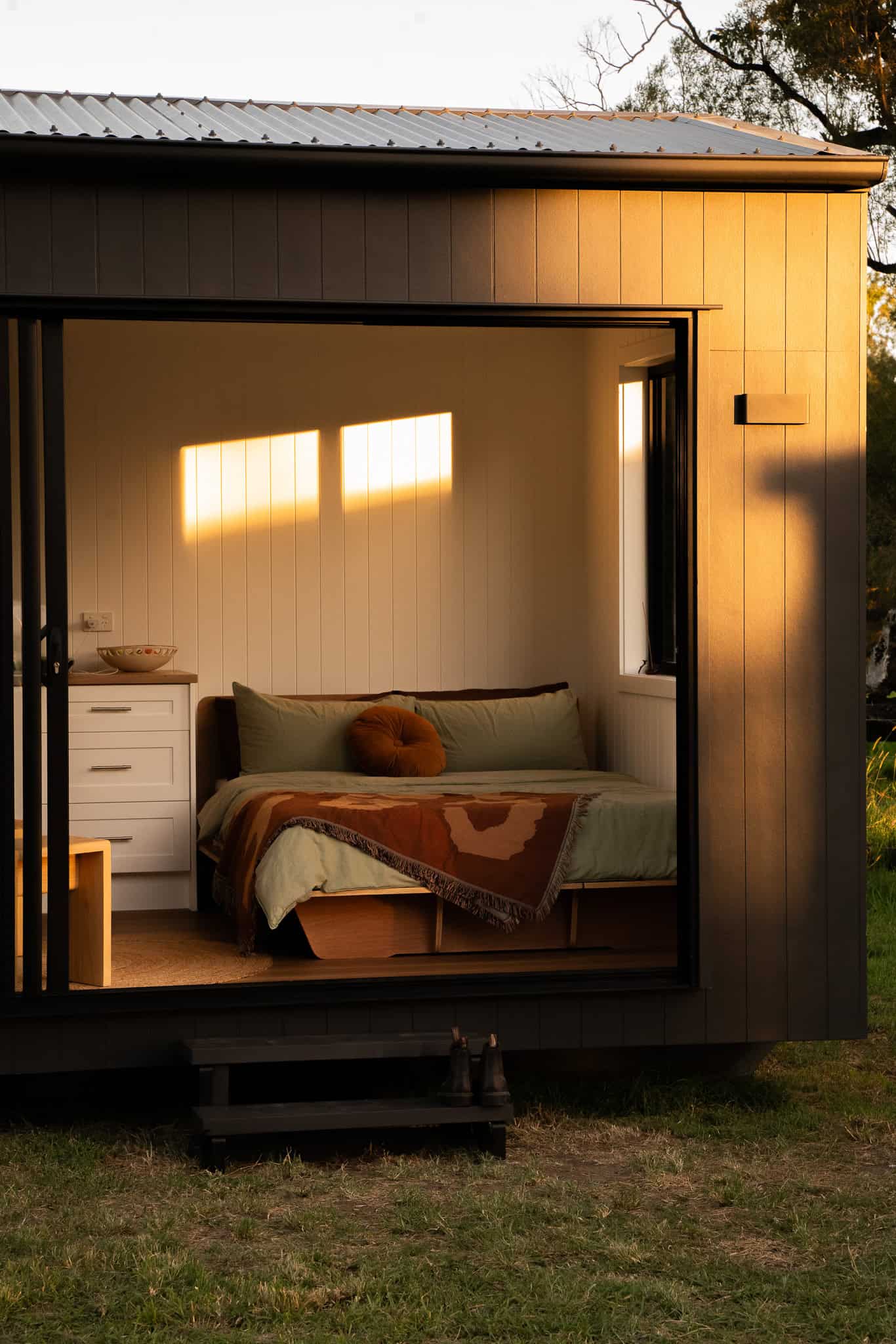 Outhaus interior at golden hour, bedroom open to the deck