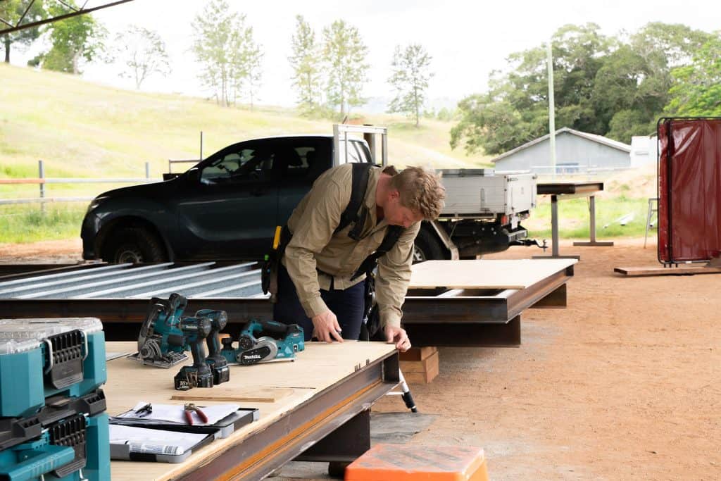 Carpenter fixing framing to a steel chassis at the Outhaus yard